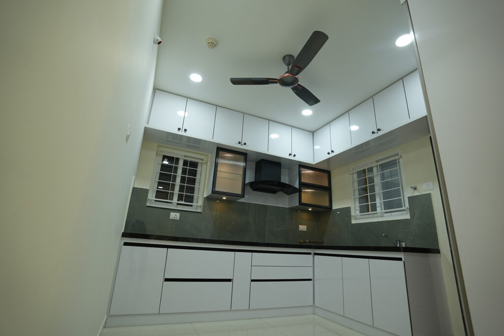 White and grey modular kitchen with overhead storage designed by IWY Designs in Hyderabad