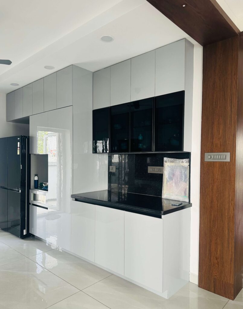 Villa kitchen interior with tall storage and black countertop by IWY Designs