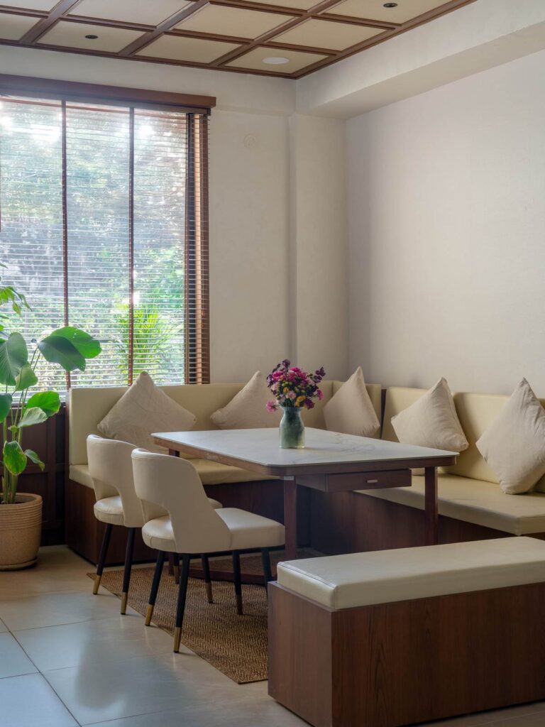OneTen cafe banquette dining corner with plants and natural light by IWY Designs Hyderabad