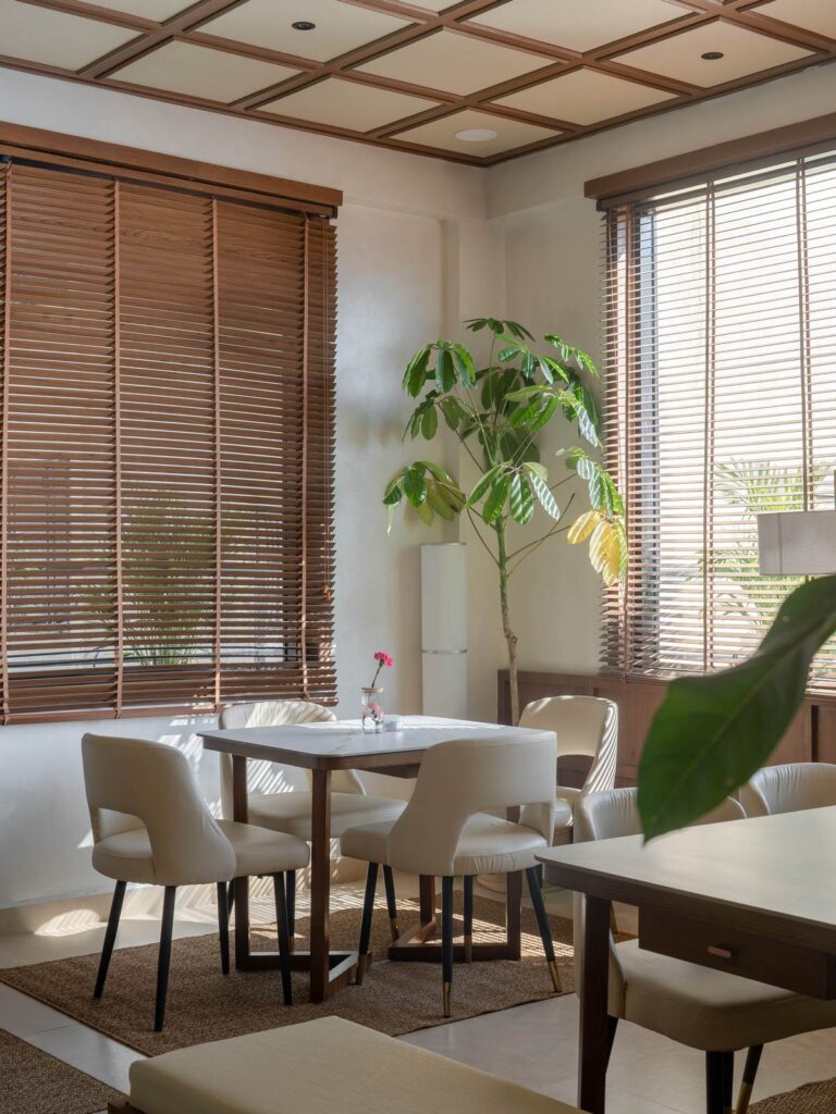 OneTen cafe corner dining table with window light and plants by IWY Designs Hyderabad