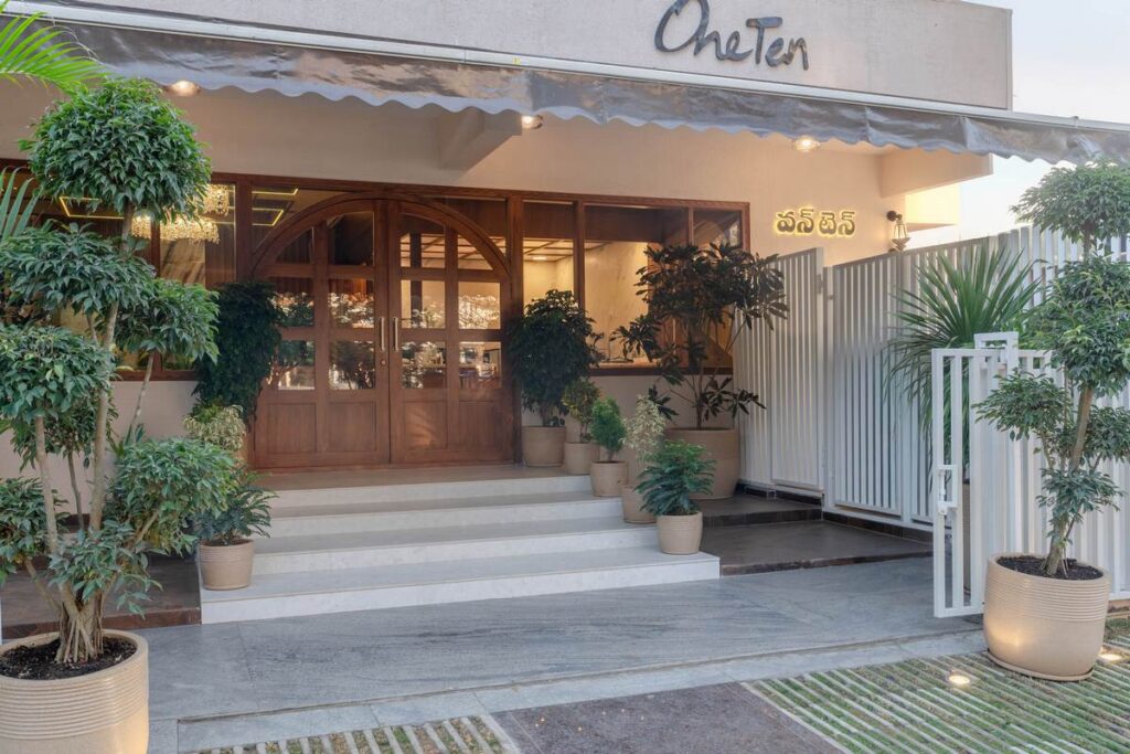 OneTen cafe entrance design with steps planters and warm commercial lighting by IWY Designs Hyderabad