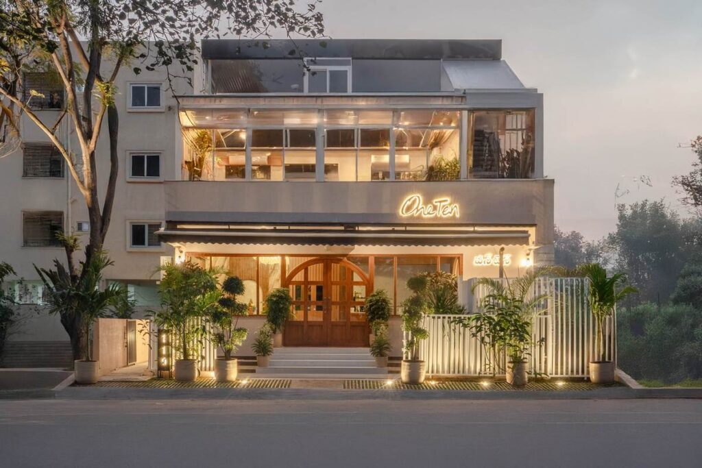 OneTen cafe exterior facade with warm lighting and greenery by IWY Designs Hyderabad