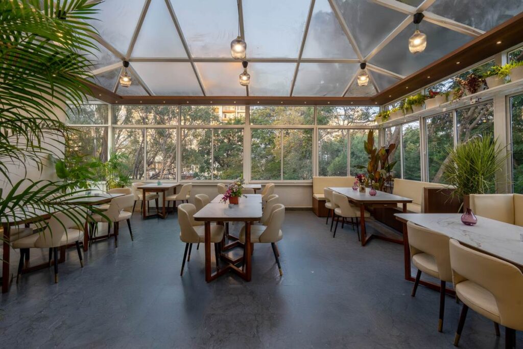 OneTen cafe gazebo seating layout with natural light and plants by IWY Designs Hyderabad