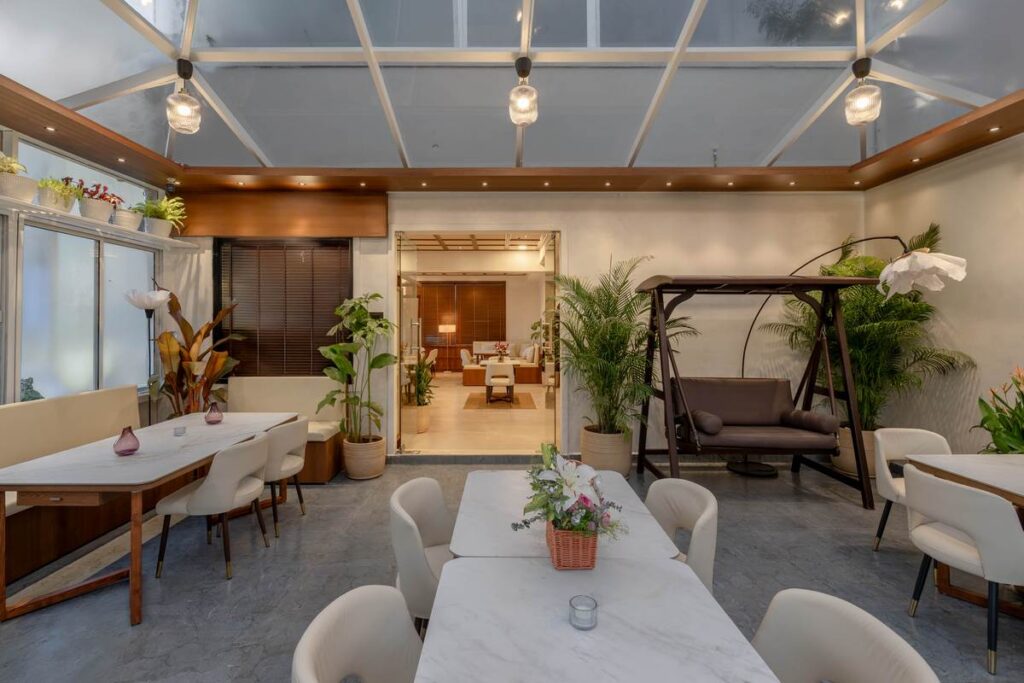 OneTen cafe indoor outdoor dining zone with warm wood finishes and plants by IWY Designs Hyderabad