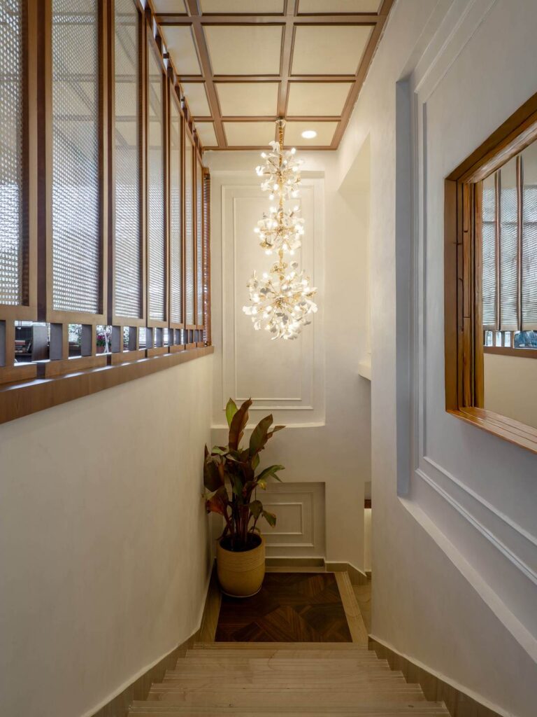 OneTen cafe staircase with chandelier detail and refined wall finishes by IWY Designs Hyderabad