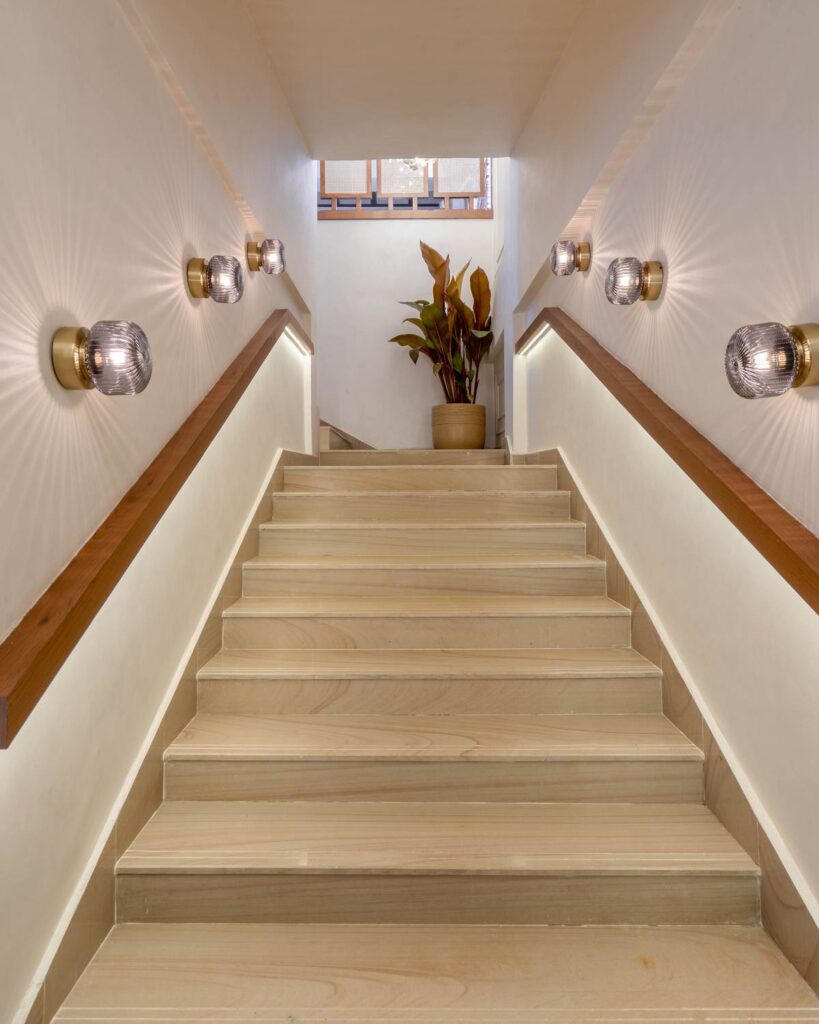 OneTen cafe staircase with warm wall lights and clear vertical circulation by IWY Designs Hyderabad